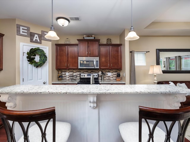kitchen featuring stainless steel appliances, light stone countertops, and a breakfast bar area