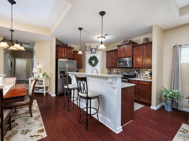 kitchen with stainless steel appliances, dark wood-type flooring, tasteful backsplash, a kitchen breakfast bar, and baseboards