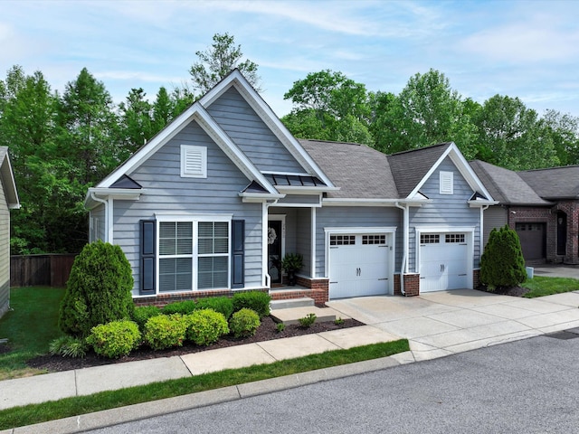 craftsman-style house featuring an attached garage, brick siding, driveway, and fence