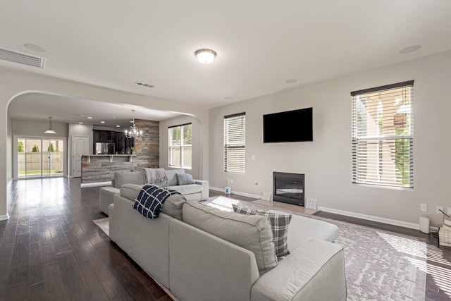 2303 Dewey Dr, Spring Hill, TN 37174 - living area featuring baseboards, dark wood-type flooring, a chandelier, arched walkways, and a fireplace with flush hearth