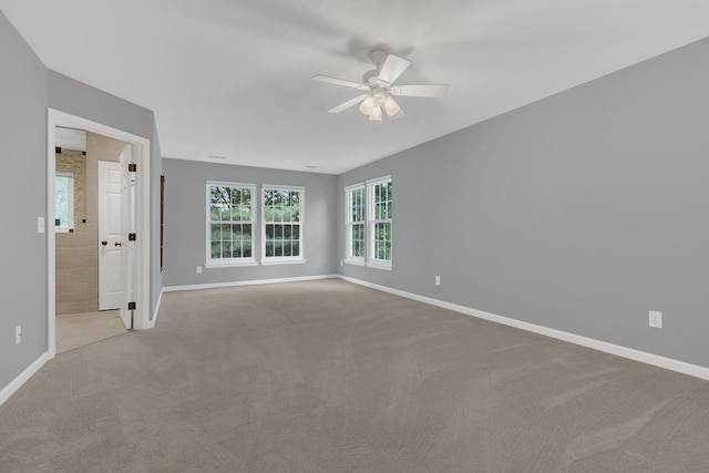 spare room with a ceiling fan, baseboards, and light colored carpet