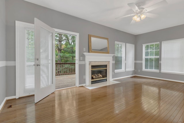 unfurnished living room with plenty of natural light, hardwood / wood-style flooring, baseboards, and a ceiling fan