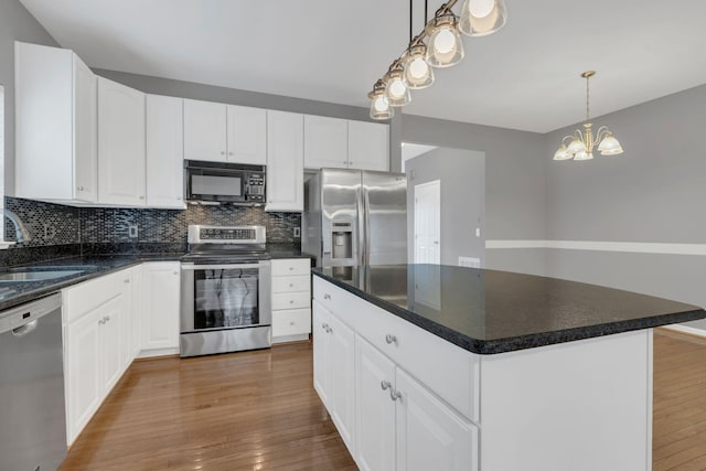 kitchen with appliances with stainless steel finishes, a sink, decorative backsplash, and wood finished floors