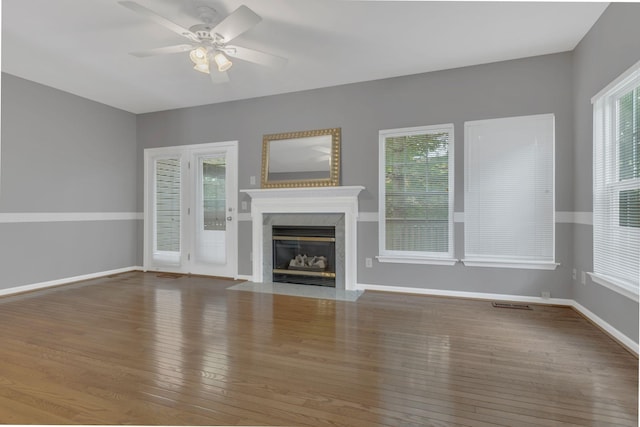 unfurnished living room featuring wood-type flooring, plenty of natural light, and ceiling fan