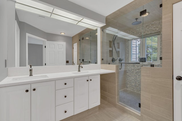 bathroom with a shower stall, double vanity, and tile patterned floors