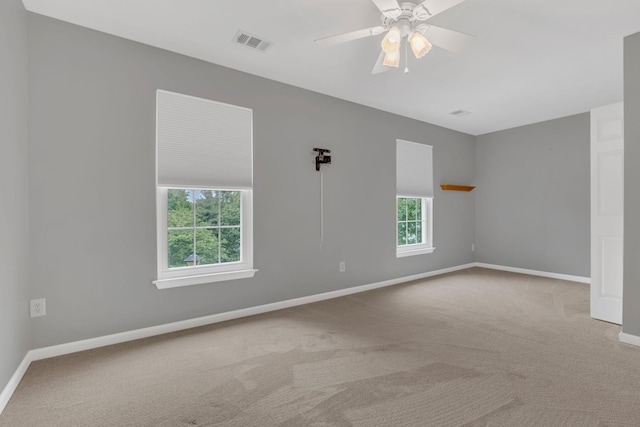carpeted spare room featuring baseboards and a ceiling fan