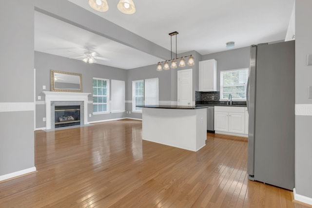 kitchen featuring appliances with stainless steel finishes, dark countertops, white cabinets, ceiling fan, and light wood-style floors