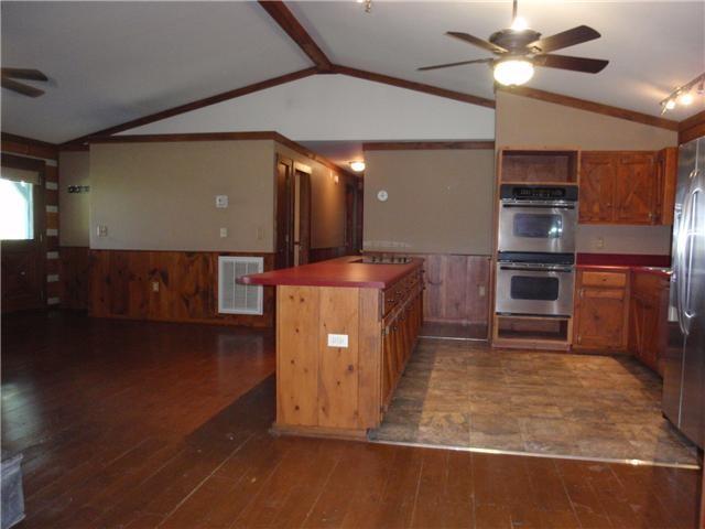 kitchen featuring ceiling fan, stainless steel appliances, wainscoting, lofted ceiling, and hardwood / wood-style floors