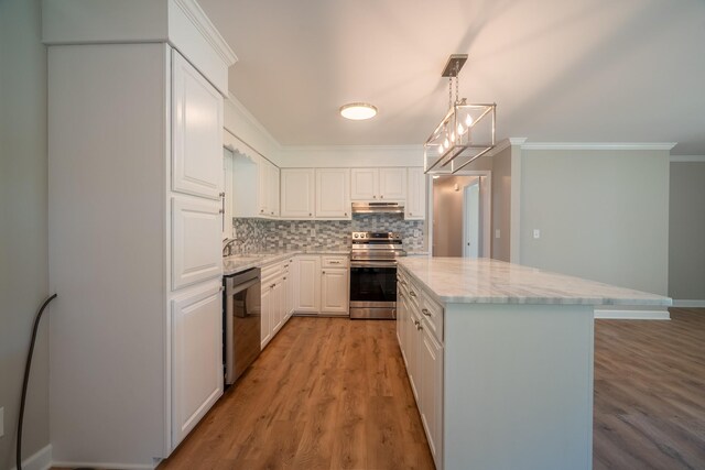 kitchen featuring appliances with stainless steel finishes, under cabinet range hood, white cabinets, light stone countertops, and crown molding