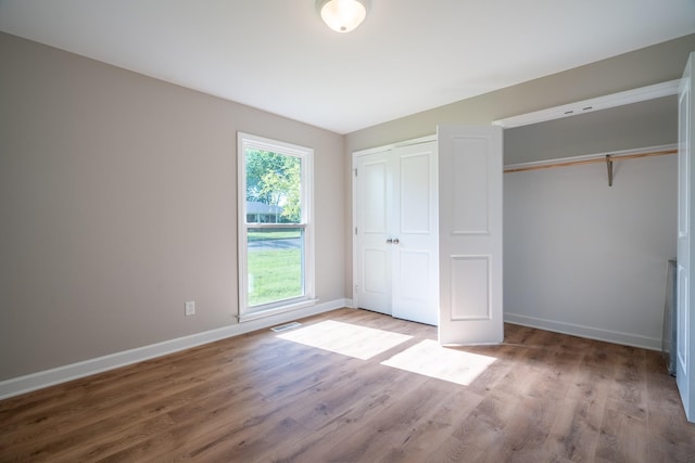 unfurnished bedroom featuring wood finished floors, baseboards, and two closets