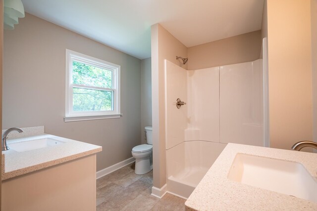 full bathroom featuring toilet, a shower, vanity, and baseboards