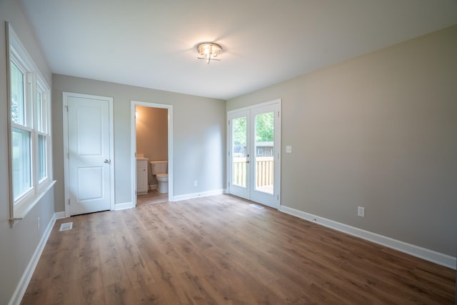 unfurnished bedroom featuring wood finished floors, baseboards, and access to outside