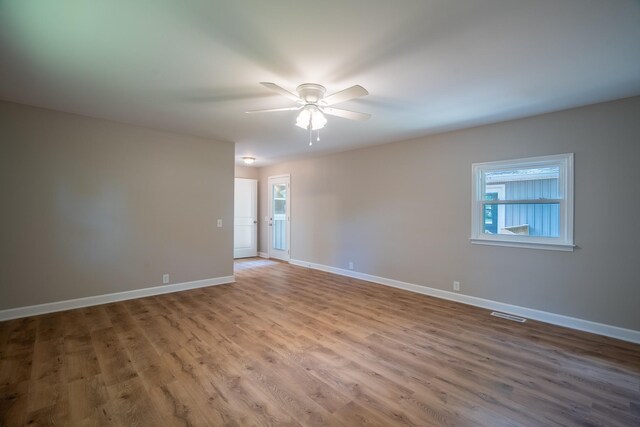 empty room featuring wood finished floors, baseboards, and a ceiling fan