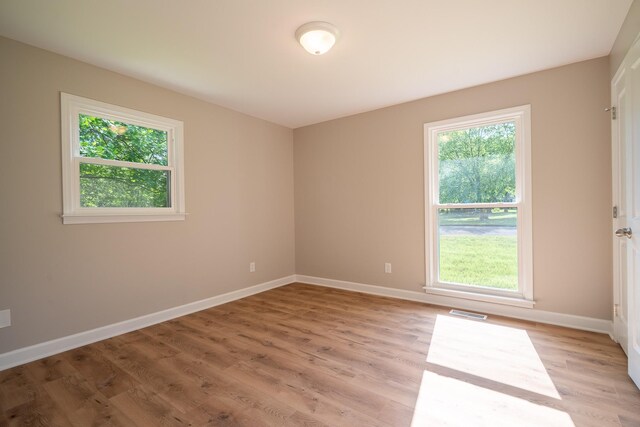 unfurnished room with healthy amount of natural light, light wood-style flooring, and baseboards
