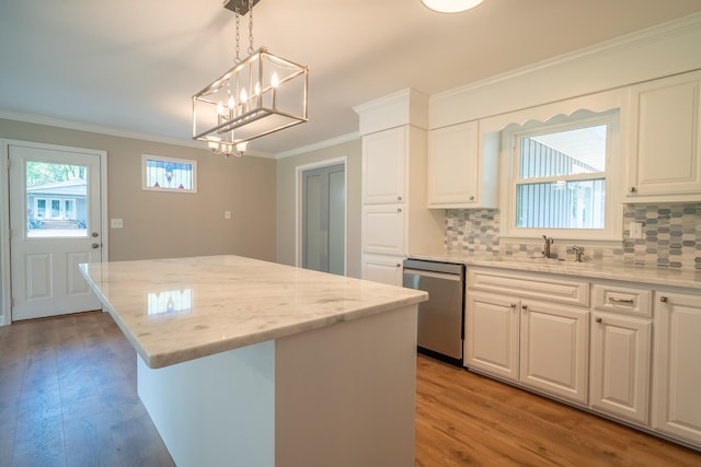 kitchen with stainless steel dishwasher, a sink, crown molding, a kitchen island, and a chandelier