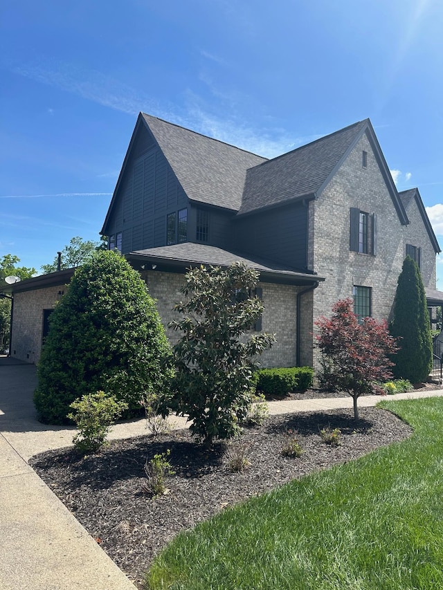 view of home's exterior with a shingled roof and brick siding