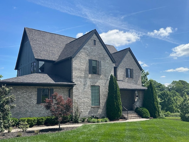 view of front of house with a front lawn, a shingled roof, and brick siding