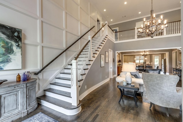 living room featuring a chandelier, stairway, a towering ceiling, crown molding, and dark wood-style flooring