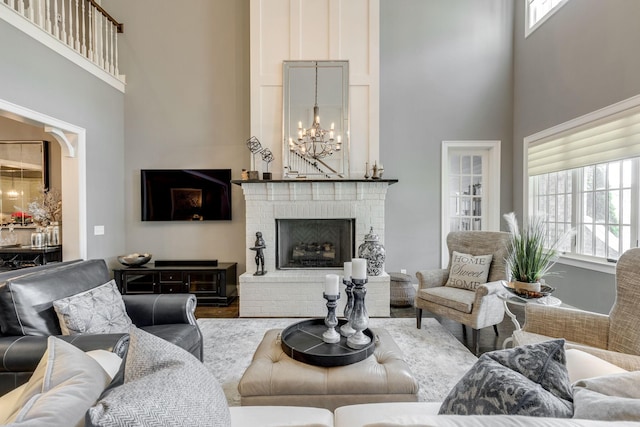 living room with a high ceiling, a chandelier, a fireplace, and wood finished floors