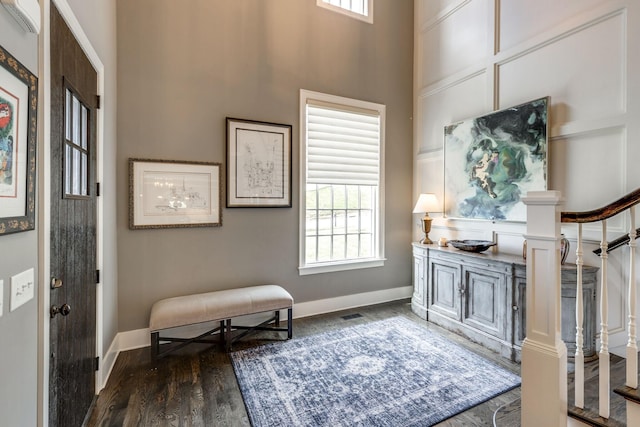 foyer with dark wood-type flooring, baseboards, and a towering ceiling