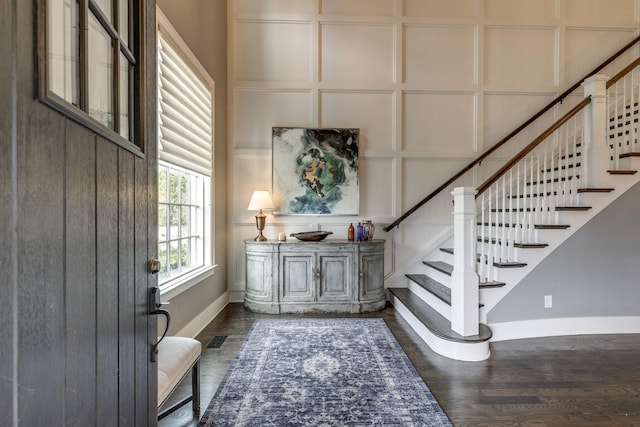 entryway with a decorative wall, stairs, and baseboards