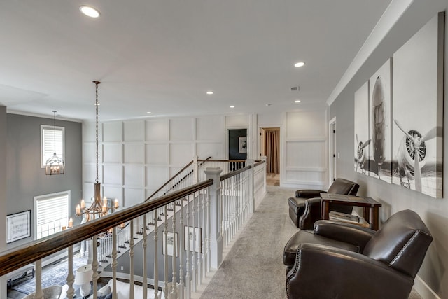 hall featuring a decorative wall, a chandelier, an upstairs landing, recessed lighting, and crown molding