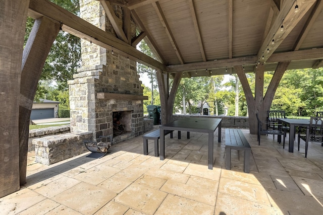 view of patio with an outdoor stone fireplace and outdoor dining space