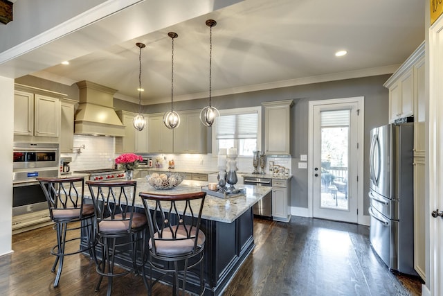 kitchen featuring stainless steel appliances, dark wood-type flooring, light stone counters, premium range hood, and ornamental molding