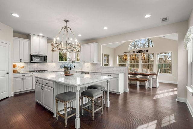 6752 Falls Ridge Ln, College Grove, TN 37046 - kitchen featuring stainless steel microwave, a chandelier, a center island, white cabinets, and tasteful backsplash