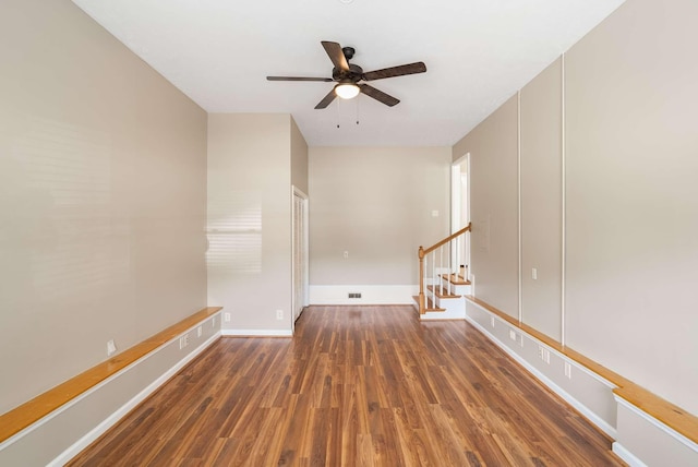 unfurnished room with wood finished floors, ceiling fan, stairway, and baseboards