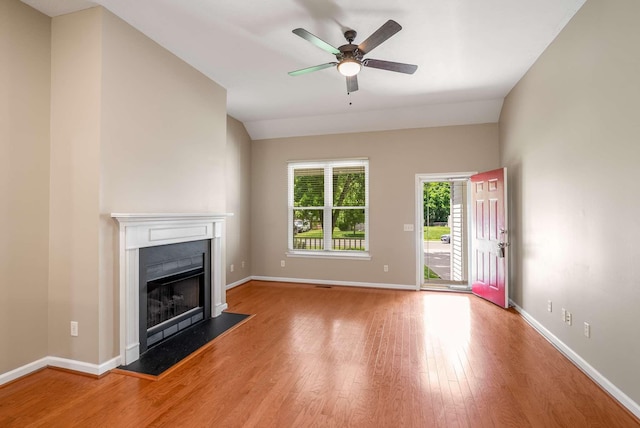 unfurnished living room with wood finished floors, a fireplace, ceiling fan, and baseboards