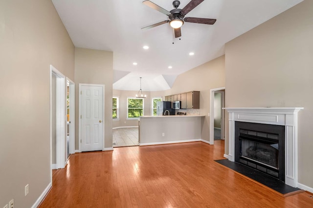 unfurnished living room featuring light wood-style flooring, ceiling fan, a fireplace, baseboards, and recessed lighting