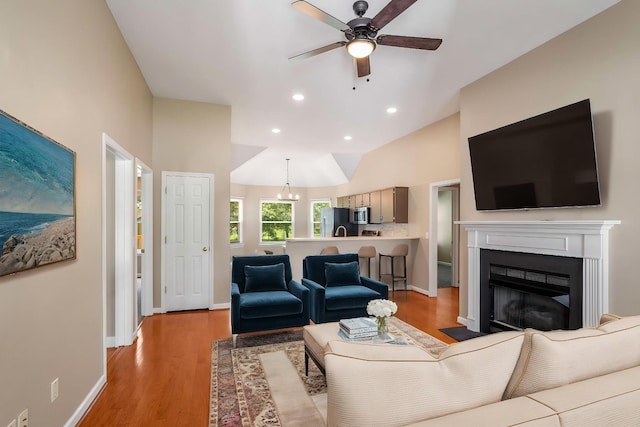 living area featuring a ceiling fan, light wood finished floors, recessed lighting, a fireplace with flush hearth, and baseboards