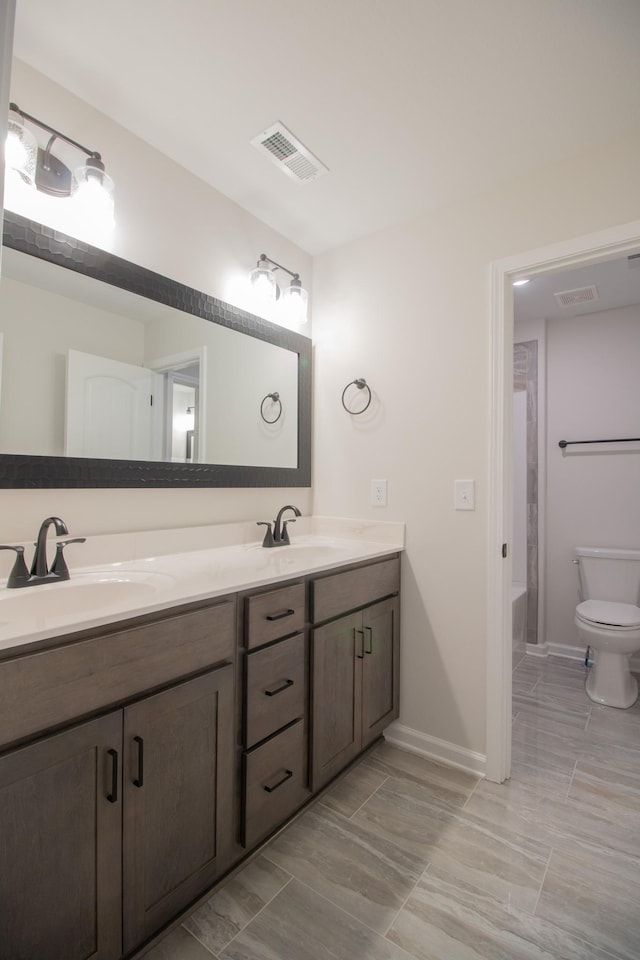 full bath with double vanity, toilet, and baseboards