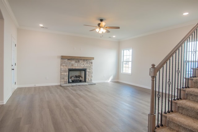 unfurnished living room featuring a ceiling fan, stairs, wood finished floors, baseboards, and crown molding