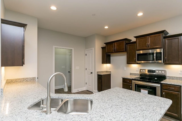 kitchen with stainless steel appliances, a sink, dark brown cabinets, recessed lighting, and dark wood-style floors