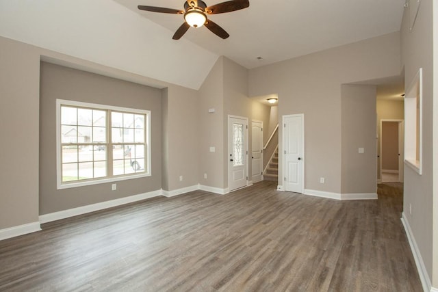 unfurnished living room featuring ceiling fan, wood finished floors, stairs, baseboards, and high vaulted ceiling