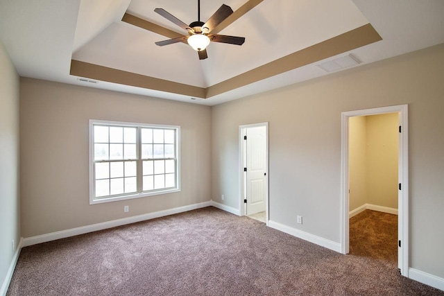 empty room featuring carpet flooring, a tray ceiling, a ceiling fan, and baseboards