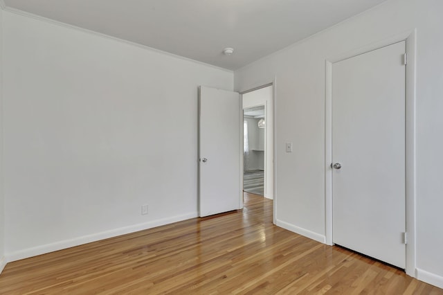 unfurnished bedroom with light wood-type flooring, crown molding, and baseboards