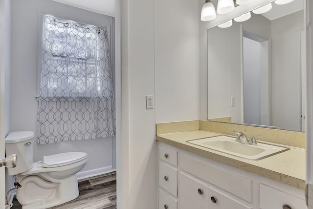 full bath with toilet, wood finished floors, and vanity