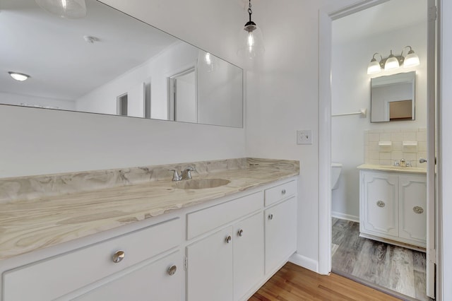 full bath with wood finished floors, vanity, baseboards, and tasteful backsplash