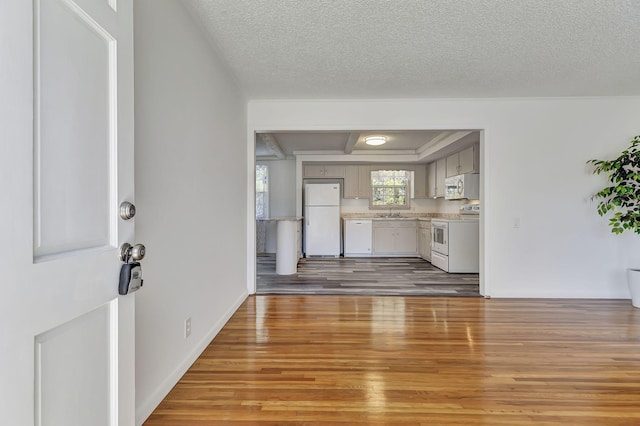 unfurnished living room featuring light wood-style floors, a sink, baseboards, and a textured ceiling