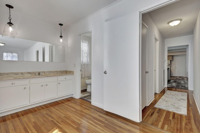 bathroom with wood finished floors, toilet, vanity, and baseboards