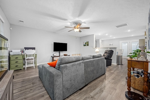 living area featuring ceiling fan, wood finished floors, a textured ceiling, baseboards, and recessed lighting