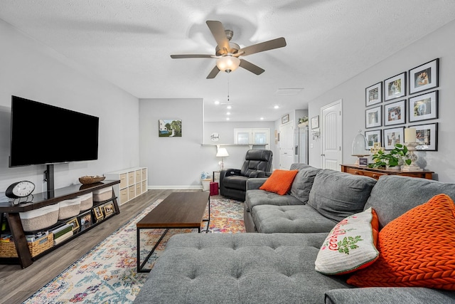 living area featuring ceiling fan, wood finished floors, baseboards, and a textured ceiling