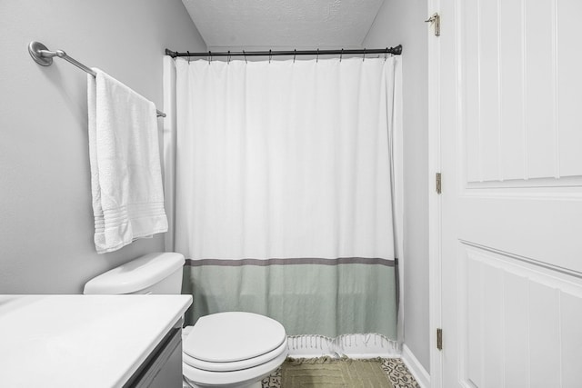 full bathroom featuring a textured ceiling, toilet, vanity, and a shower with curtain