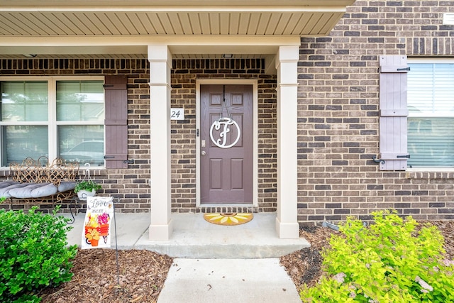 doorway to property featuring brick siding and a porch