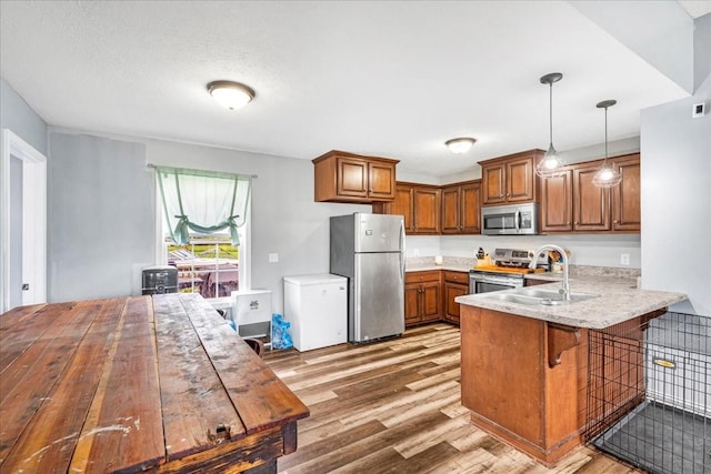 890 Akersville Rd, Lafayette, TN 37083 - kitchen featuring appliances with stainless steel finishes, wood finished floors, brown cabinetry, and a sink