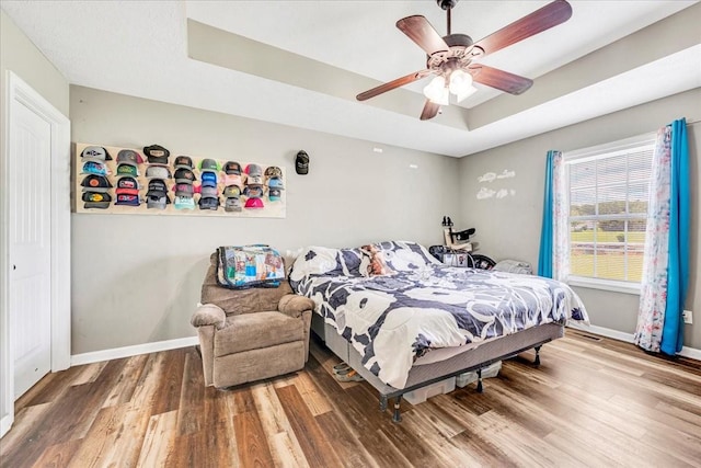 890 Akersville Rd, Lafayette, TN 37083 - bedroom featuring wood finished floors, baseboards, a tray ceiling, and a ceiling fan
