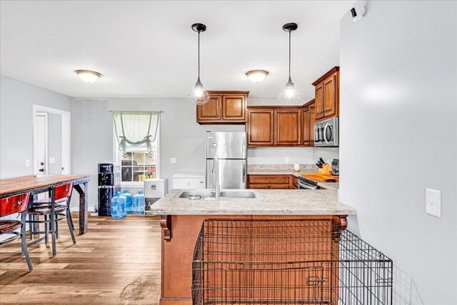 890 Akersville Rd, Lafayette, TN 37083 - kitchen with appliances with stainless steel finishes, brown cabinetry, a peninsula, a sink, and light wood-type flooring